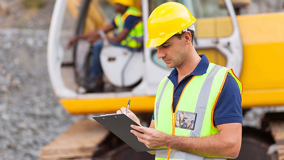 Workers in safety vests and hard hats in a meeting.